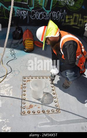 Avant que les travailleurs entrent dans l'espace confiné à l'intérieur du barrage de Sepulveda pour faire leur inspection, Charles Fouty, opérateur de réparation d'équipement de barrage avec les États-Unis Armée corps of Engineers district de Los Angeles, enlève une plaque au-dessus du barrage pour évacuer le gaz causé par la créosote 22 mars à Van Nuys, Californie. Après le retrait de la plaque, de grands flexibles de ventilation ont été insérés pour éliminer toute accumulation de gaz. Le personnel du district a récemment suivi une formation pour travailler dans des espaces confinés. Le barrage a subi une inspection de la structure hydraulique en acier 22-23 mars. (Photo de John Reese, États-Unis Armée corps des ingénieurs Los Angeles Distr Banque D'Images