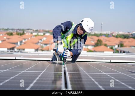 Ingénieur sur le toit agenouillé à côté des panneaux solaires photovoltaïque avec l'outil à portée de main pour l'installation Banque D'Images