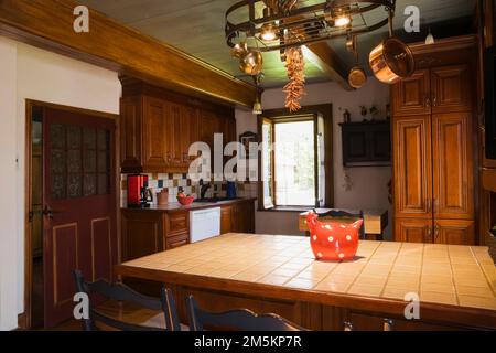 Île supérieure en céramique Tan avec deux vieux siège tissé de style bistro en bois avec coussins chaises dans la cuisine à l'intérieur de la maison en rondins reconstruite des années 1840. Banque D'Images