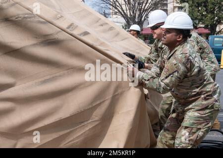 Le Sgt Jerry Dunn, chef de commandement de l'escadre de transport aérien 374th, aide à retirer l'ancienne housse de protection contre la pluie de tente d'essai COVID-19 lors de son démantèlement à la base aérienne de Yokota, au Japon, en 23 mars 2022. Le retrait de la tente permettra de disposer d’une plus grande place de stationnement pour les patients à l’hôpital de base et de fournir des soins plus confortables et plus efficaces à l’intérieur de l’établissement. Banque D'Images