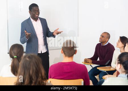 Professeur à l'université devant le tableau de surveillance avec des étudiants multinationaux Banque D'Images