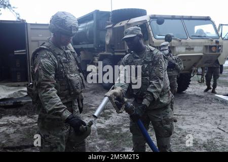 Le lieutenant-colonel Jonathan Daniels, commandant du bataillon du bataillon de soutien de la division 87th, Brigade de soutien de la division 3rd, détient une cantine tandis que le PFC Nigel Dundas, spécialiste de la purification de l'eau affecté à la Compagnie Alpha, 87th DSSB, Remplit une cantine pour goûter l'eau purifiée pendant la formation de trois jours sur la purification de l'eau à fort Stewart, Géorgie, sur 24 mars 2022. La capacité de purifier l'eau est une fonction unique de Alpha Co., l'ORD de 3rd au sein de la Division. Banque D'Images