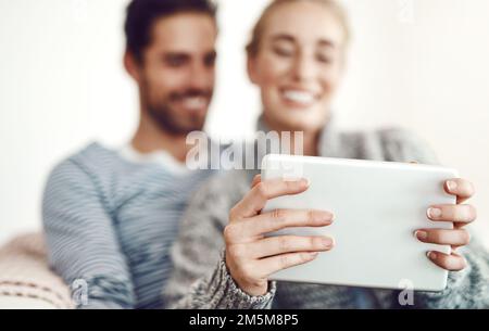 Vous serez toujours divertis si vous avez une bonne connexion. un jeune couple utilisant une tablette numérique sur son canapé à la maison. Banque D'Images