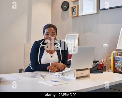 Ne vous inquiétez pas, je suis au travail. Portrait d'une femme d'affaires assise à son bureau et travaillant sur un ordinateur portable. Banque D'Images