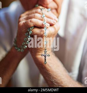 En maintenant la foi. Plan court un homme âgé tenant un rosaire dans la prière. Banque D'Images