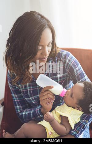 S'assurer qu'elle n'a jamais faim. une jeune mère qui allaite sa petite fille à la maison. Banque D'Images