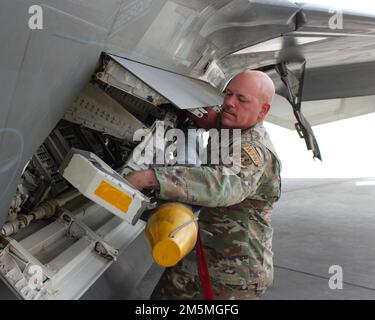 ÉTATS-UNIS Le Sgt. Jason Fitts, chef principal de la Force aérienne, est nommé chef du Groupe de soutien de la mission expéditionnaire de 380th. Il aide à charger une munition d'entraînement sur un F-22 Raptor, ainsi que le Brig. Le général Andrew Clark, commandant de l'escadre expéditionnaire aérien de 380th, et un spécialiste des armes F-22. Fitts est sur le point de prendre sa retraite après une carrière de 29 ans dans l'Armée de l'Air, dont la première moitié a été consacrée comme spécialiste des armes. Banque D'Images