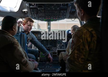 ÉTATS-UNIS Le premier Airman Colton Bingle de la Force aérienne, deuxième de gauche, un technicien des systèmes intégrés de navigation de communication de l'escadron 517th du transport aérien, explique les fonctions des commandes de vol d'un C-17 Globemaster III affecté à l'escadron 517th du transport aérien pendant l'opération Mission Connect à la base interarmées Elmendorf-Richardron, Alaska, 25 mars 2022. L’opération Mission Connect est une excursion d’immersion organisée pour donner aux aviateurs l’occasion d’en apprendre davantage sur la mission de l’escadron de maintenance des aéronefs 703rd. Banque D'Images