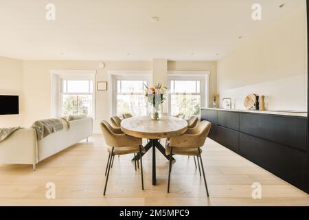 cuisine et salle à manger dans un salon moderne avec murs blancs, parquet et grandes fenêtres donnant sur le balcon Banque D'Images