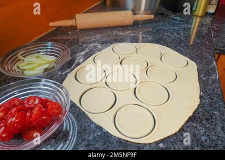 Cuisine souabe, préparation de mini dinnete, également dennete, dinnede, dennete, copieuse, salées, coupées les blancs de pâte à levure, la pâte à levure brute, les tomates Banque D'Images