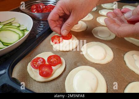 Cuisine souabe, préparation de mini dinnete, également dennete, dinnede, dennete, copieuse, pâte de levure salée, crue, recouverte de légumes, de tomates Banque D'Images