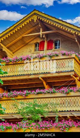 Ancienne maison en bois avec fleurs sur le balcon dans les Alpes suisses Banque D'Images