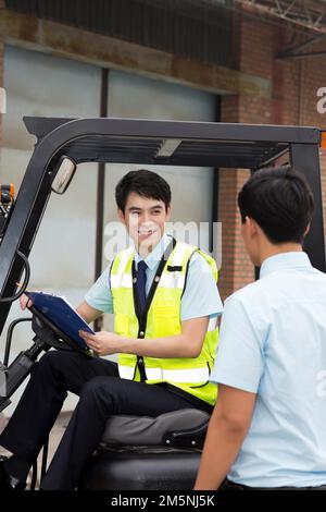 Le personnel de gestion de l'entrepôt logistique parle pour conduire un chariot élévateur Banque D'Images