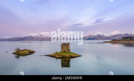 Castle Stalker, Argyll, Écosse, dressé sur son île intertidale dans le Loch Laich avec le paysage dramatique des Highlands au loin. Banque D'Images
