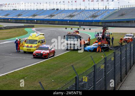 Vue de la scène après un grave accident de course, gauche ambulance jaune, devant la voiture médicale rouge de l'événement de course, à côté de lui camion de remorquage et Banque D'Images