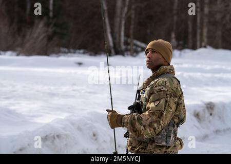 Un garde-boue national de l'Armée de l'Alaska affecté au détachement de services techniques de 207th surveille un nouveau CASQUE UH-60 Blackhawk lors d'un exercice d'entraînement sur le terrain d'opérations conjointes au Camp Mad Bull sur la base conjointe Elmendorf-Richardson, Alaska, le 26 février 2022. L'exercice consistait en des opérations de transport aérien, la construction de positions de combat défensives dans l'arctique et une attaque simulée contre les armes légères visant à évaluer et à renforcer les interventions de la Force aérienne et du personnel de la Garde nationale de l'Armée de l'Alaska. Des exercices conjoints démontrent la coopération, améliorent l'interopérabilité et renforcent la dissuasion. Banque D'Images