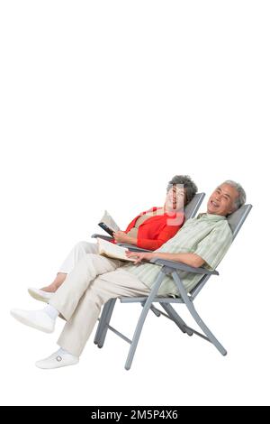 Heureux couple âgé assis sur une chaise de plage Banque D'Images