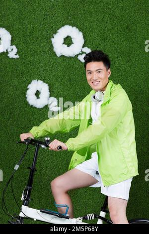 Le jeune homme créatif herbe à vélo Banque D'Images