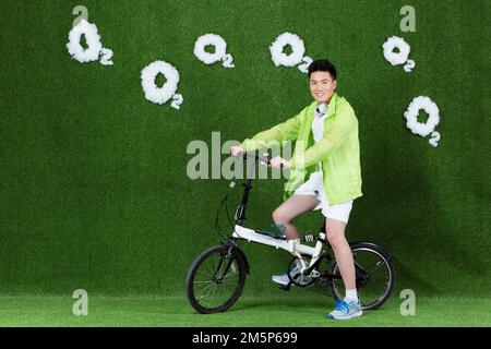 Le jeune homme créatif herbe à vélo Banque D'Images