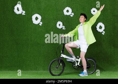 Le jeune homme créatif herbe à vélo Banque D'Images