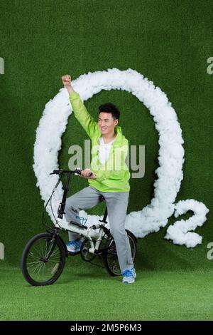 Le jeune homme créatif herbe à vélo Banque D'Images