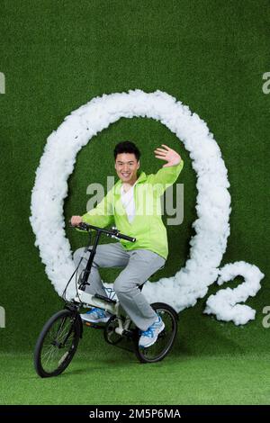 Le jeune homme créatif herbe à vélo Banque D'Images