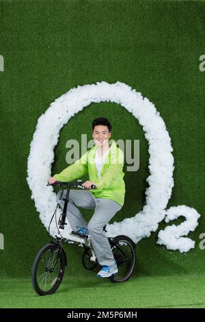 Le jeune homme créatif herbe à vélo Banque D'Images