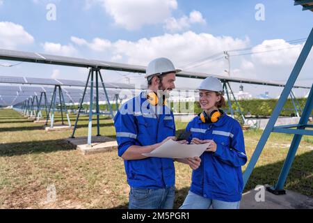 Ingénieur à la ferme solaire en temps de pause regardant les médias sociaux drôles de téléphone mobile et rire Banque D'Images