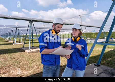 Ingénieur à la ferme solaire en temps de pause regardant les médias sociaux drôles de téléphone mobile et rire Banque D'Images