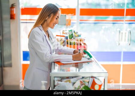 pharmacien femme travaillant à écrire avec un stylo et un presse-papiers en pharmacie Banque D'Images