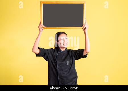 une femme asiatique souriante se lève et montre un tableau noir vierge Banque D'Images