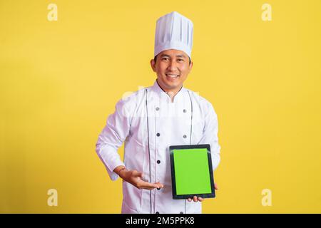 chef masculin portant une veste de chef montrant un écran de tablette vierge Banque D'Images