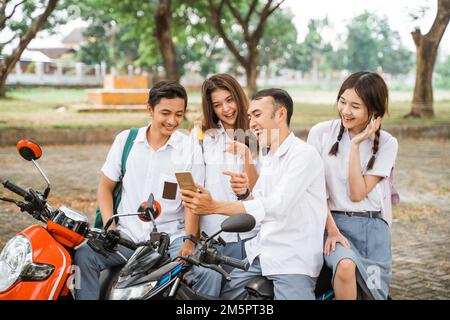 Quatre élèves du secondaire se sont mis à selfie en utilisant des smartphones ensemble sur moto Banque D'Images