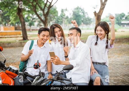 Quatre heureux lycéens se réjouissent de la remise des diplômes en moto Banque D'Images