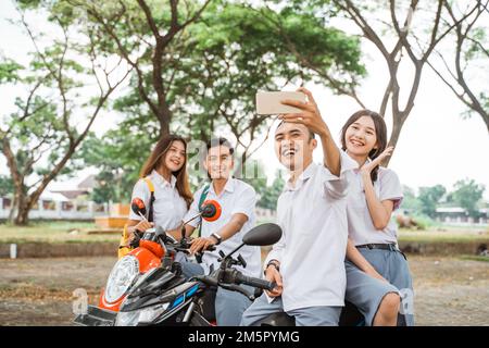 Deux élèves du secondaire d'un couple asiatique se sont assis à moto Banque D'Images