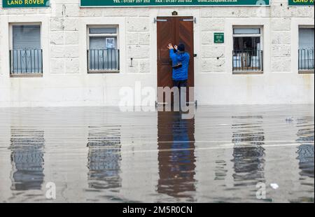 Un commerçant ferme son magasin à Whitesands, Dumfries, en raison des inondations causées par le débordement de la rivière Nith. Un avertissement météorologique ambre de fortes pluies a été émis pour une partie de l'Écosse, alors que le met Office a déclaré que le cyclone mortel qui a provoqué une chute de température aux États-Unis provoque maintenant des conditions météorologiques humides et venteuses au Royaume-Uni. Date de la photo: Vendredi 30 décembre 2022. Banque D'Images