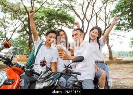 Heureux élève de lycée selfie à l'aide d'un smartphone célébrant la remise des diplômes Banque D'Images