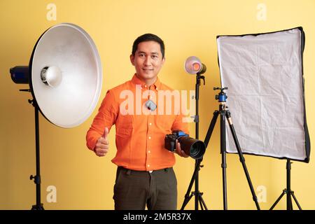 photographe debout avec les pouces et tenant l'appareil photo Banque D'Images