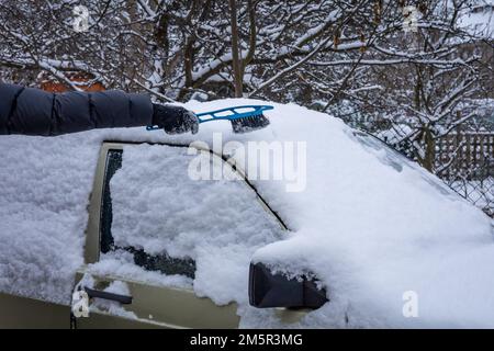 Nettoyage de la neige du toit de voiture en hiver. Ancienne Mercedes Benz classique 190D. Banque D'Images