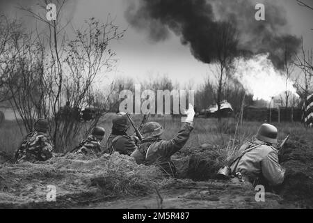 Position défensive. Les réacteurs ont armé des fusils et se sont habillés comme soldats allemands de l'infanterie Wehrmacht de la Seconde Guerre mondiale combattant de manière défésive dans le Trench. Bâtiment Banque D'Images