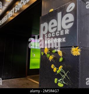 NEW YORK, NEW YORK — 30 décembre 2022: Des fleurs sont vues en hommage à la dernière star brésilienne de football Pele à l'extérieur du magasin Pele de football de Times Square. Banque D'Images