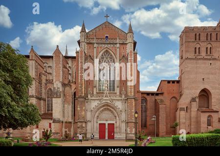 Face nord de la cathédrale Saint Etienne de Toulouse avec contreforts gothiques en briques, rosace et chemin de jardin sous ciel nuageux Banque D'Images