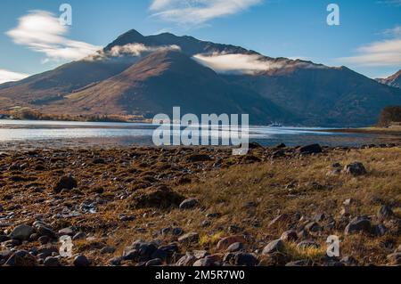 Des nuages bas pendent sur les montagnes au-delà des eaux calmes du Loch Leven, le matin d'automne Banque D'Images