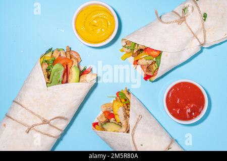 Classique rue nourriture shawarma ou burrito, sandwich sain enveloppé dans la tortilla pain plat avec viande de poulet frite, légumes frais, sauce, sur b vif Banque D'Images