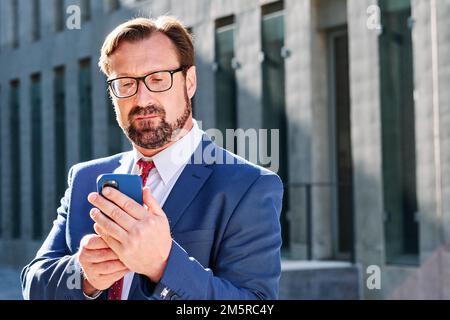 Homme d'affaires concentré utilisant le mobile à l'extérieur Banque D'Images