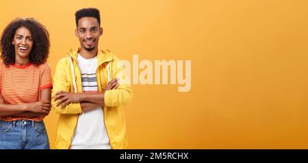 Portrait d'une femme afro-américaine sarcastique surprise avec une coiffure afro-américaine debout avec un petit ami croisant les bras sur la poitrine riant de scorn et Banque D'Images