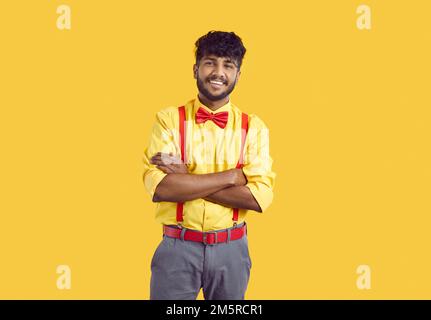Portrait studio du jeune Indien heureux en chemise jaune, bretelles rouges et noeud papillon Banque D'Images
