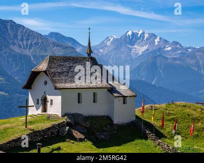 Une église de Bettmeralp avec des drapeaux cantonaux suisses, située au-dessus de la vallée du Rhône en haute-Valais en Suisse Banque D'Images