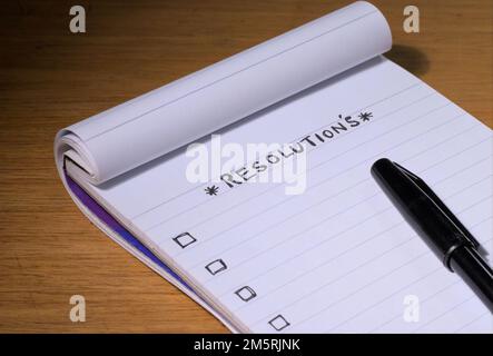 RÉSOLUTION Écrite sur un bloc-notes ou un livre avec un stylo sur une table. Banque D'Images