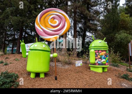 Statues Android de lylipop et de jelly bean devant de grands arbres dans le jardin Banque D'Images